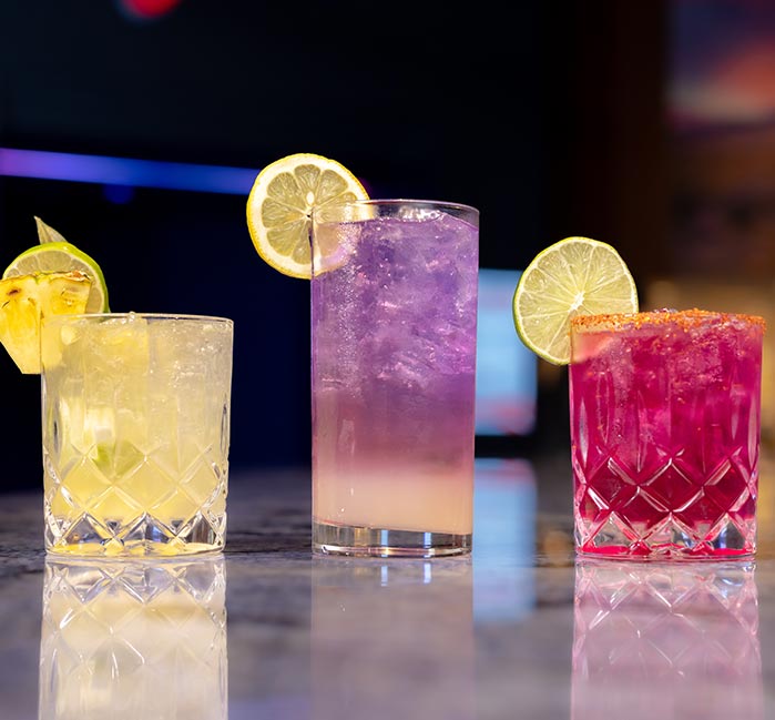 Three colorful cocktails arranged on a bar counter.