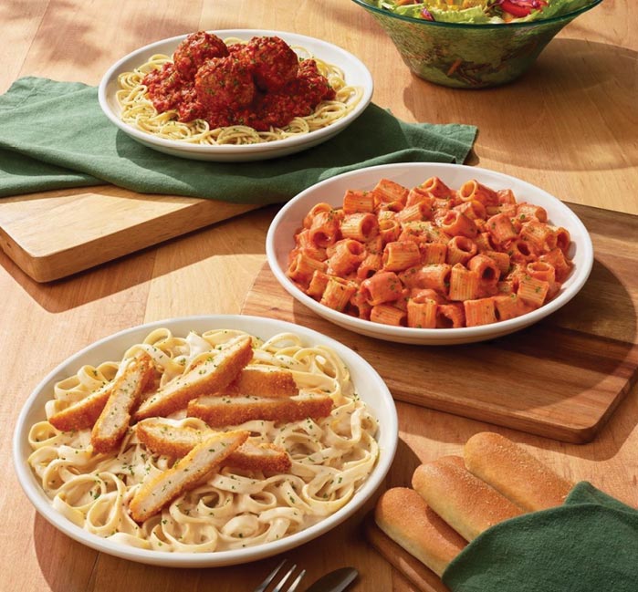 Three pasta dishes on a table from Olive Garden.